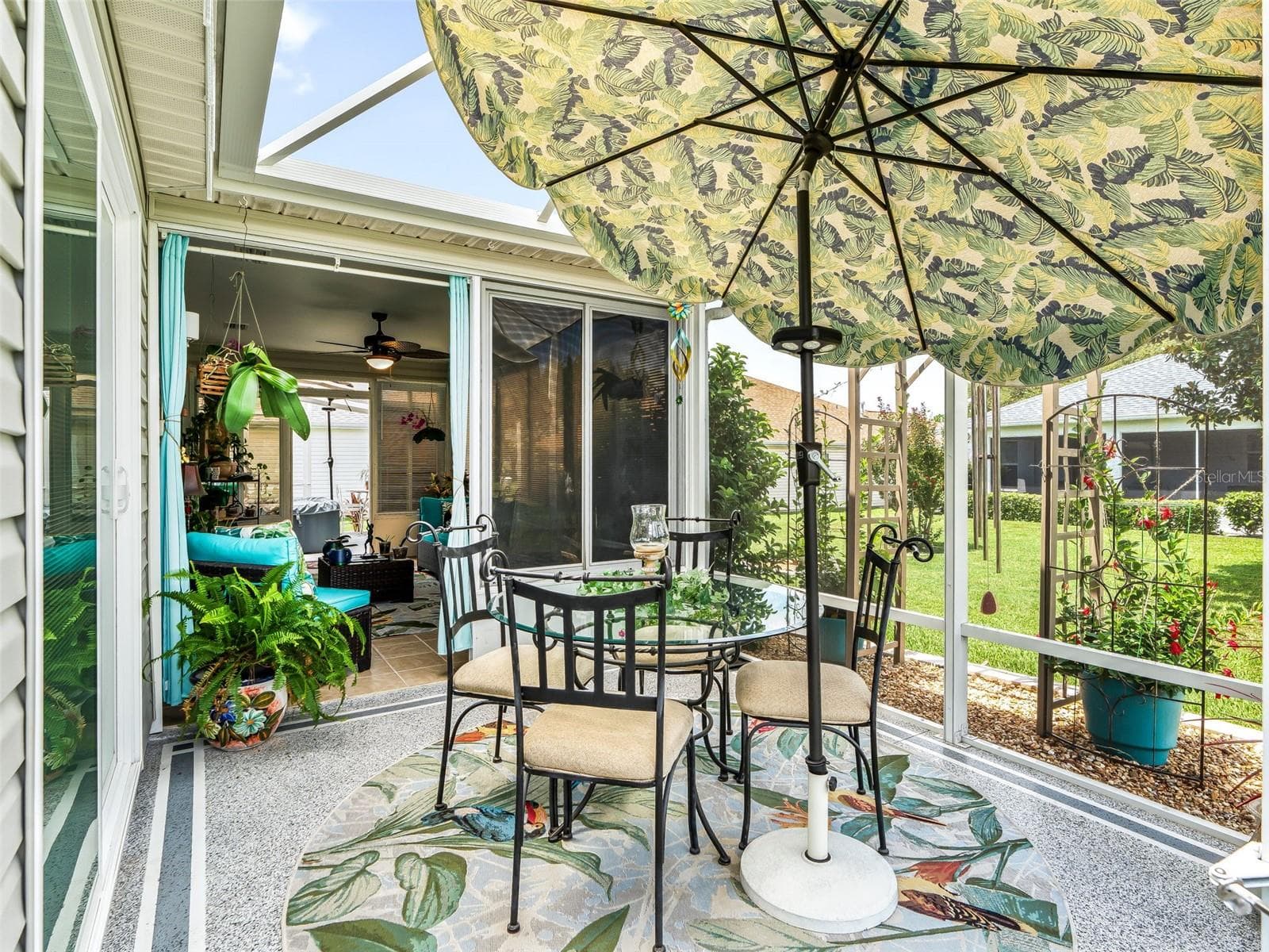 Another angle of the charming patio beneath a decorative canopy umbrella offers a comfortable setting for outdoor dining, morning coffee, or casual entertaining. Birdcage is roofed with clear Florida plexiglass for a dry environment! - 17946 SE 87TH MELROSE CT, THE VILLAGES