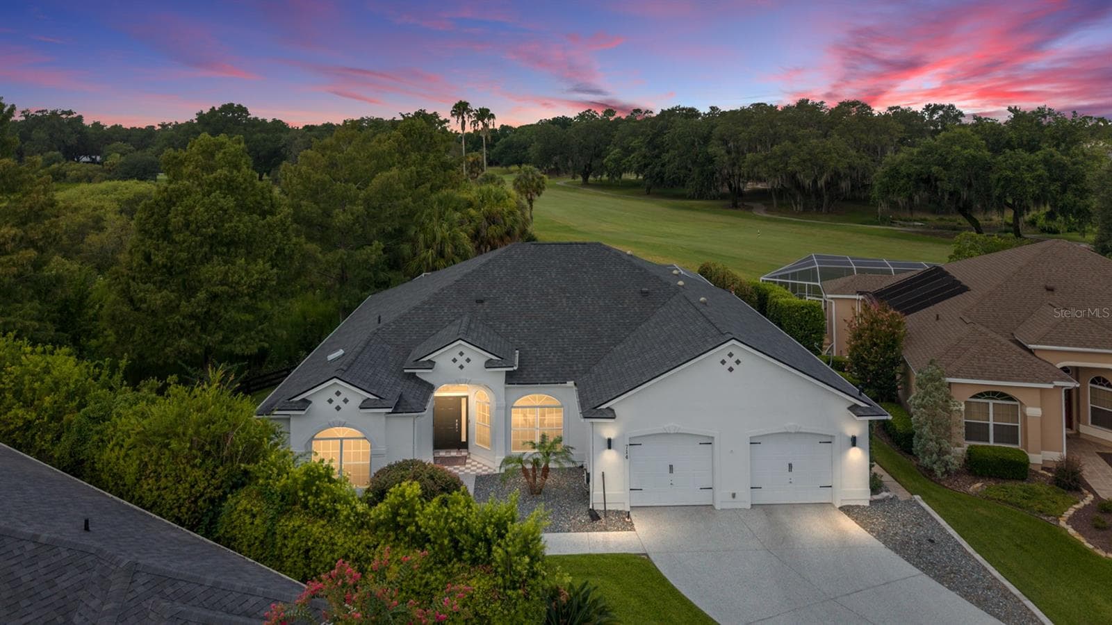 A striking sunset backdrop and warm exterior lighting create an inviting evening view of this golf course home. - 714 CIMARRON AVE, THE VILLAGES