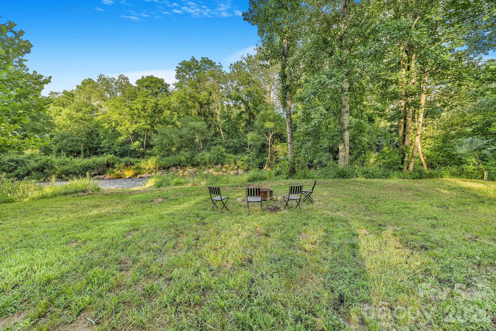Enjoy conversations at the fire pit beside the creek. - Waynesville