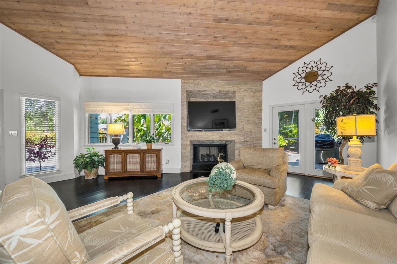 Living room with gas fireplace and tongue and groove volume ceiling! The french doors lead to the screened outdoor patio and grill area overlooking the serene pond. - 10497 LONGWOOD DR, SEMINOLE