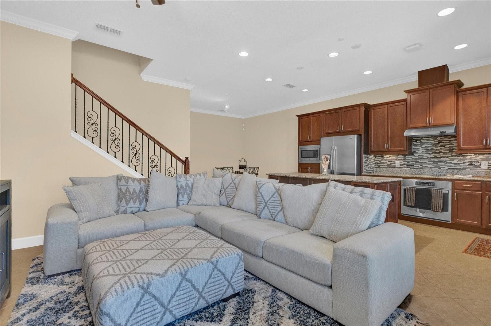 Spacious open-concept living room with an oversized sectional, ideal for entertaining. - 9219 LAUREATE BLVD, ORLANDO