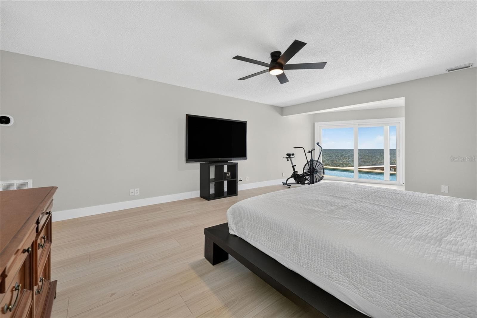 Expansive primary bedroom with sliding glass doors that open to the pool deck and showcase stunning waterfront views. - 2936 68TH AVE S, ST PETERSBURG