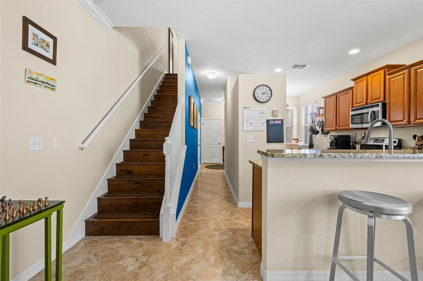 Wood stair treads add warmth to the first floor, while the breakfast bar offers a convenient seat just outside the kitchen. - 9524 TRUMPET VINE LOOP, NEW PORT RICHEY