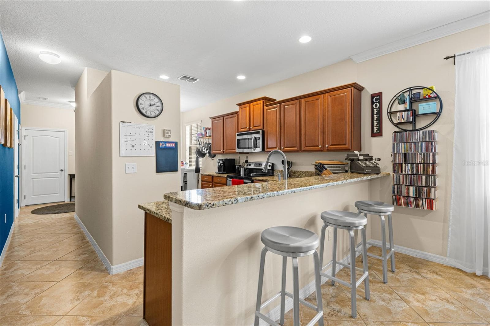 The generous breakfast bar comfortably seats three, adding an easy place for coffee, quick meals or conversation while dinner is underway. - 9524 TRUMPET VINE LOOP, NEW PORT RICHEY