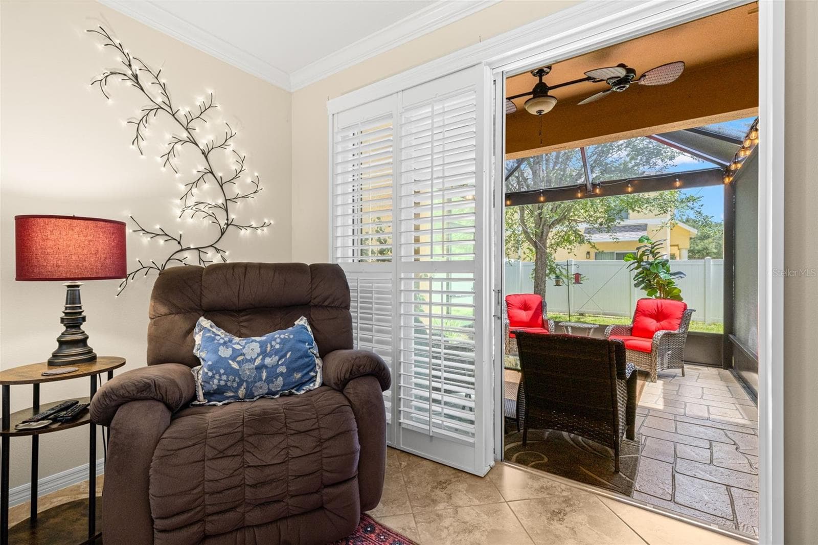 Plantation shutters frame the doors to the new screened lanai, creating an easy extension of the living room with stamped concrete flooring and a ceiling fan. - 9524 TRUMPET VINE LOOP, NEW PORT RICHEY