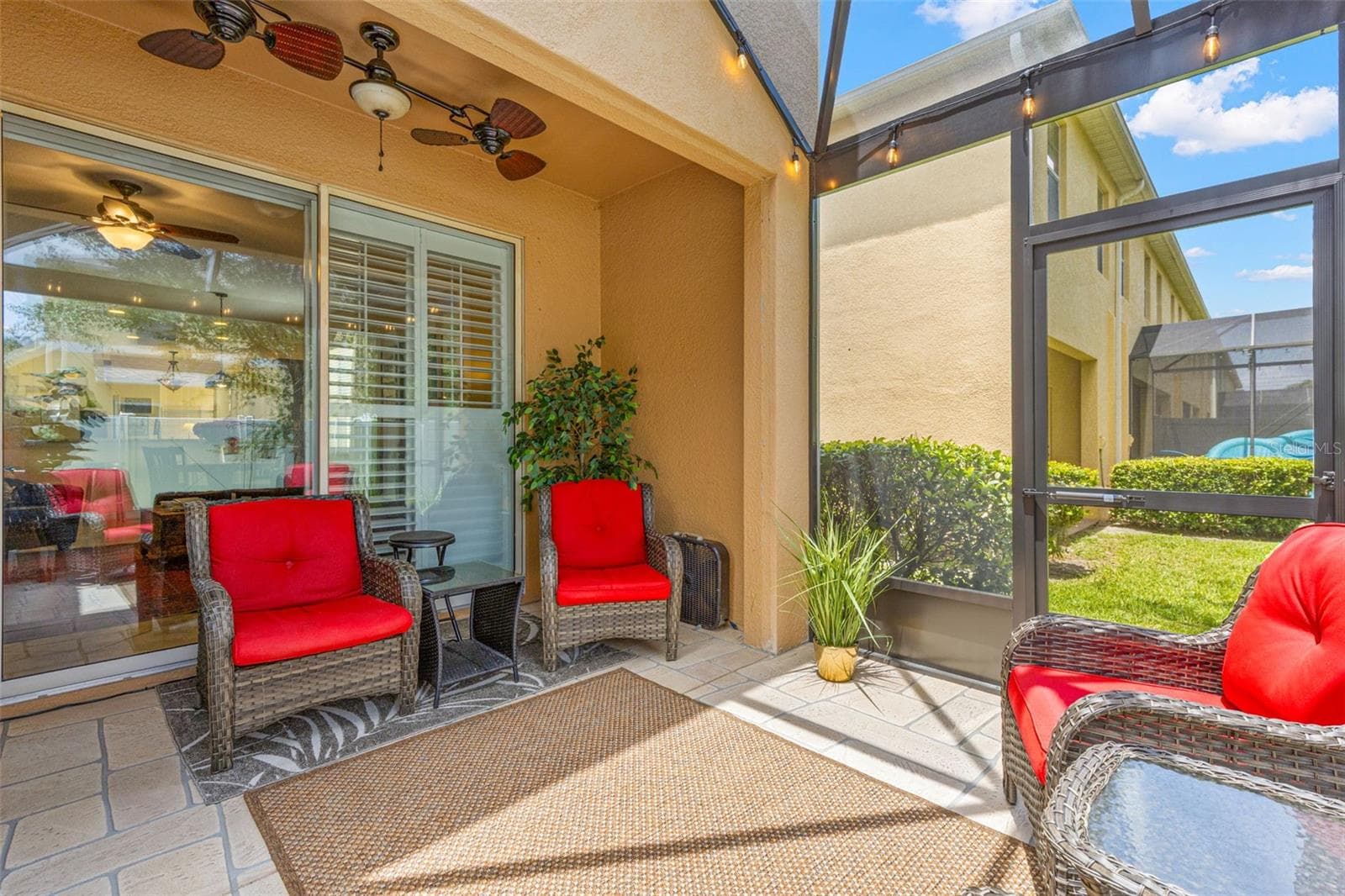 The screened lanai includes a covered seating area with a ceiling fan overhead, creating a comfortable spot to relax outdoors in shade and breeze. - 9524 TRUMPET VINE LOOP, NEW PORT RICHEY