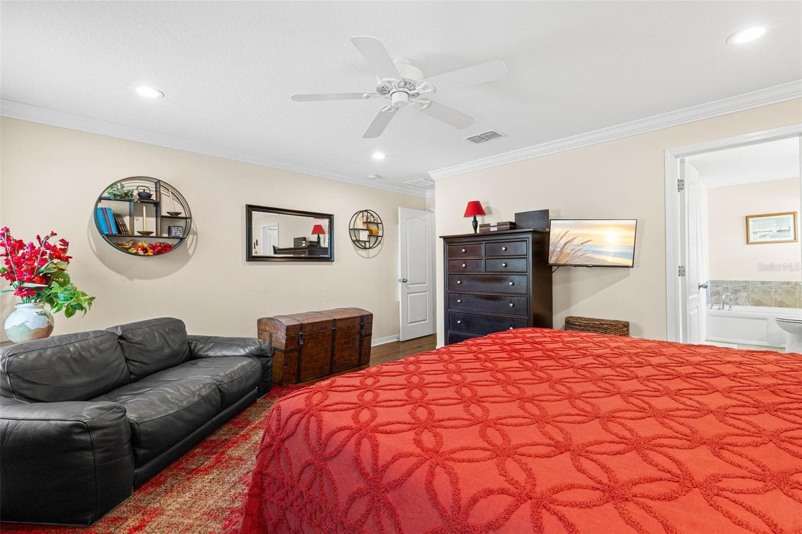Another view of the primary suite highlights its generous proportions, hardwood flooring, crown molding and direct access to the en suite bath. - 9524 TRUMPET VINE LOOP, NEW PORT RICHEY
