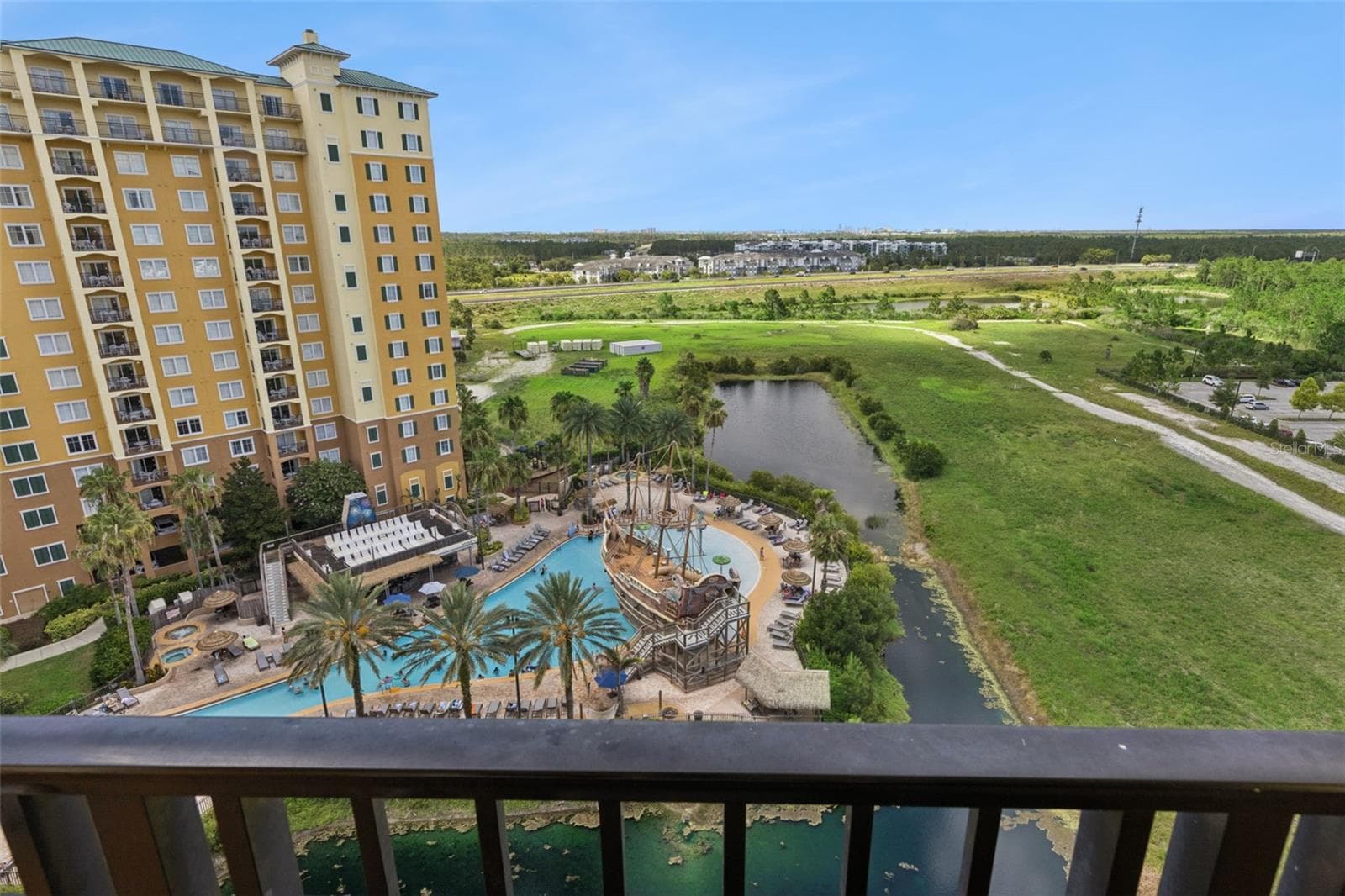 Balcony View | The private balcony offers expansive views of the pool, pond, and open green space beyond. - 8101 RESORT VILLAGE DR #31110, ORLANDO