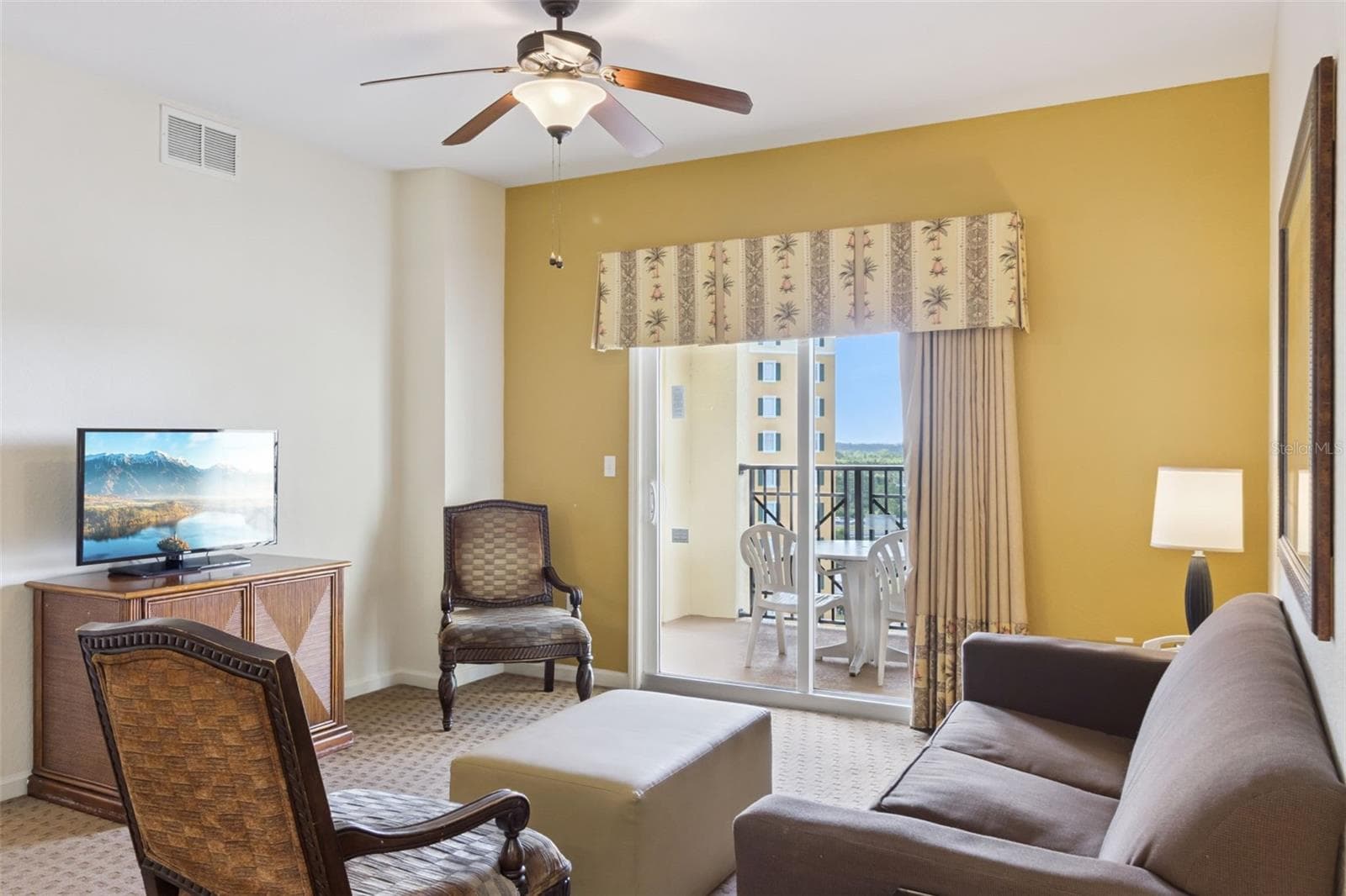Living Room | Sliding glass doors fill the living area with natural light and provide direct access to the covered balcony. - 8101 RESORT VILLAGE DR #31110, ORLANDO