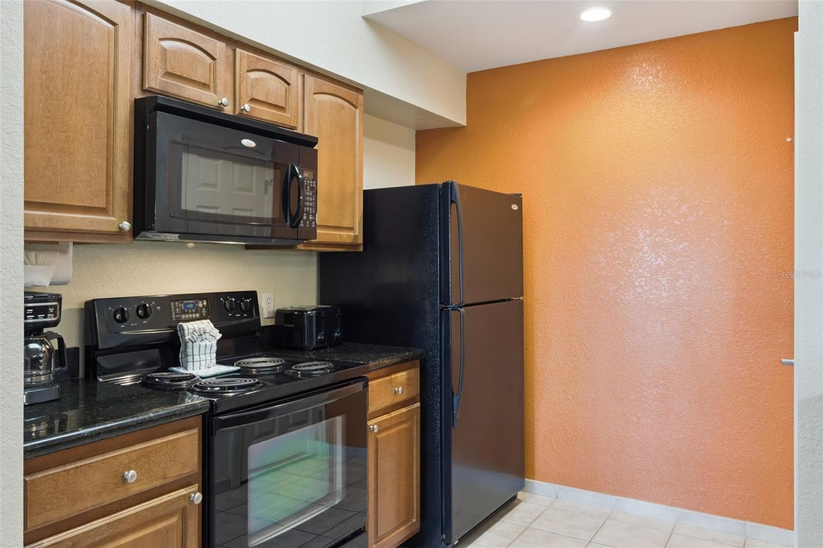 Kitchen Appliances | The kitchen includes a range, built-in microwave, and refrigerator. - 8101 RESORT VILLAGE DR #31110, ORLANDO