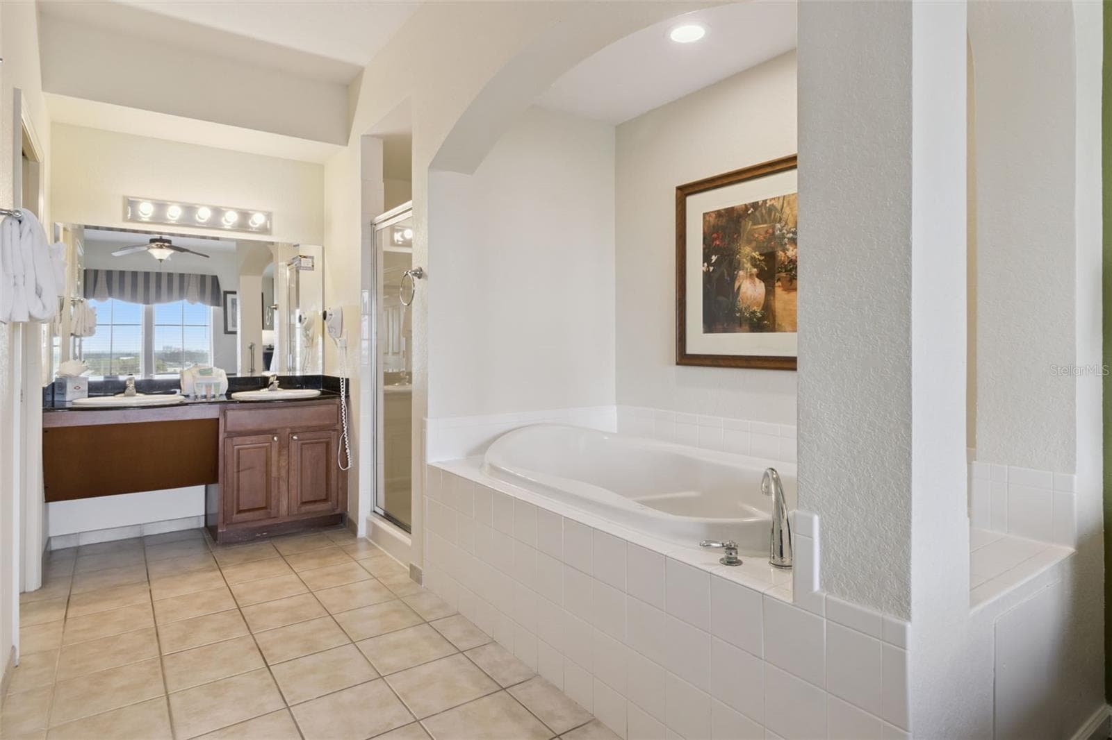 Primary Bathroom | Tile flooring, a soaking tub, and a separate vanity area provide ample space for daily routines. - 8101 RESORT VILLAGE DR #31110, ORLANDO
