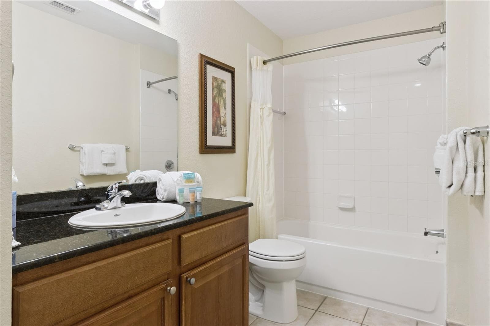 Guest Bathroom | The secondary bath features a vanity with granite countertops, wood cabinetry, and a full tub-and-shower combination. - 8101 RESORT VILLAGE DR #31110, ORLANDO