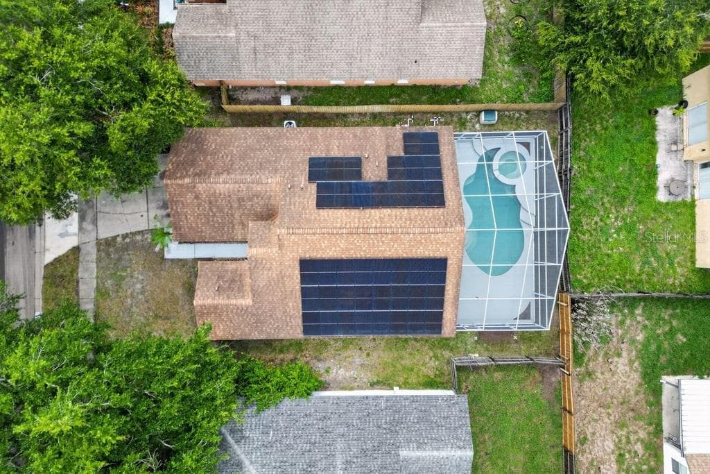 Aerial view of the home featuring rooftop solar panels and a screen-enclosed pool. - 97 ABBEY HOLLOW DR, APOPKA