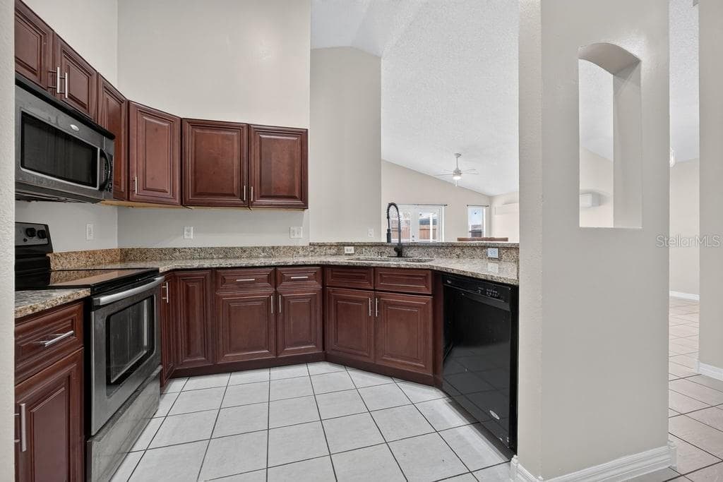 Kitchen with wood cabinetry, stainless steel appliances, and a breakfast bar. - 97 ABBEY HOLLOW DR, APOPKA