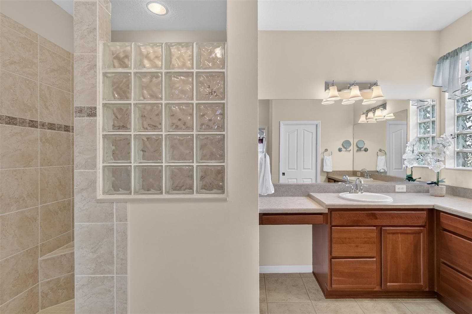 En-suite bath featuring dual vanities, a ROMAN SHOWER, linen closet, and a private water closet. - 2693 IRIS WAY, THE VILLAGES