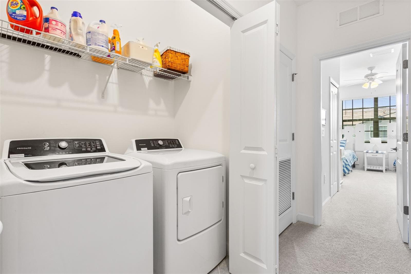 The upstairs laundry area is equipped with a washer, dryer, and shelving for supplies - 14275 PINE LODGE LN, FORT MYERS