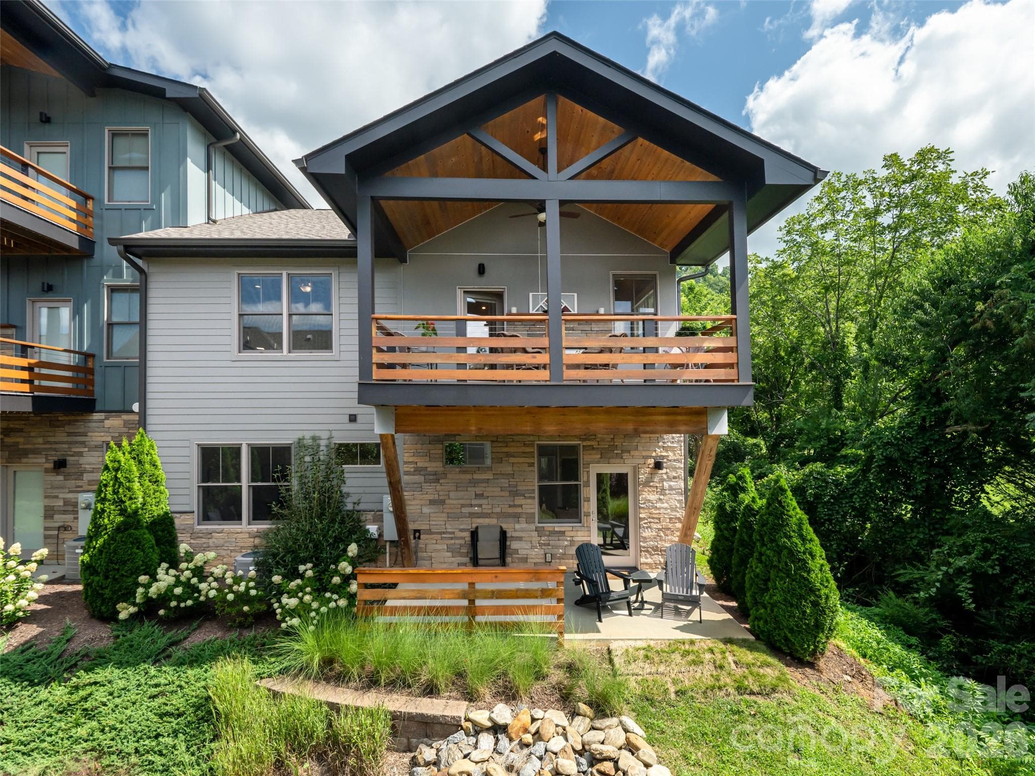 Two story deck overlooking the private wooded area and river rock stream. Upstairs deck is covered with stylish wooden ceiling. Great privacy on lower level patioas lower patio. Lower patio perfect for guests offering privacy and views - 309 Ava Lane, Asheville