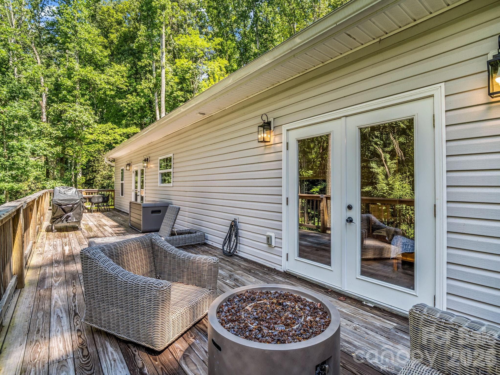 The Frenchdoor in the foreground leads to the primary bedroom. The propane gas firepit and wicker furniture, cushions and cushion bin are also available for purchase. - 180 Ridgeview Drive, Hendersonville