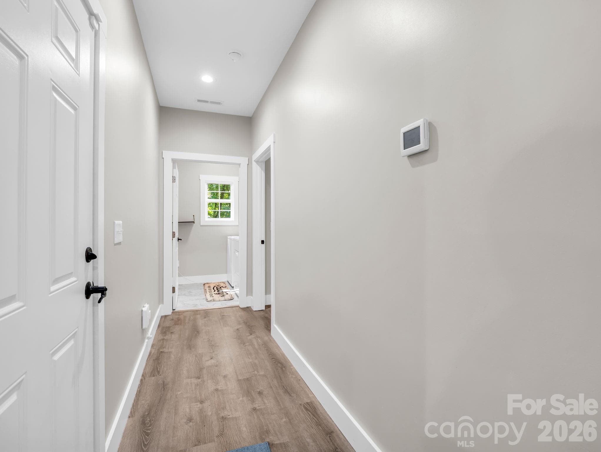 Hallway to laundry room straight ahead and primary bedroom on the right. Door on the left leads to the garage. - 180 Ridgeview Drive, Hendersonville