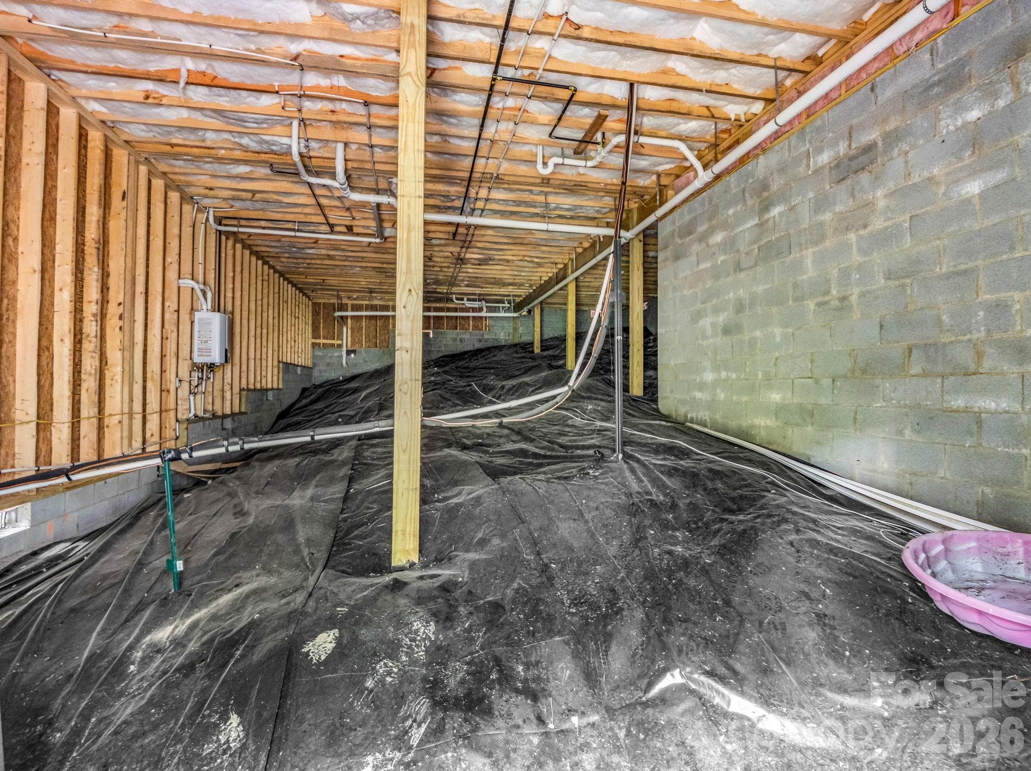 Large crawlspace with moisture barrier. Rinnai on demand gas hot water heater is on the left wall. - 180 Ridgeview Drive, Hendersonville