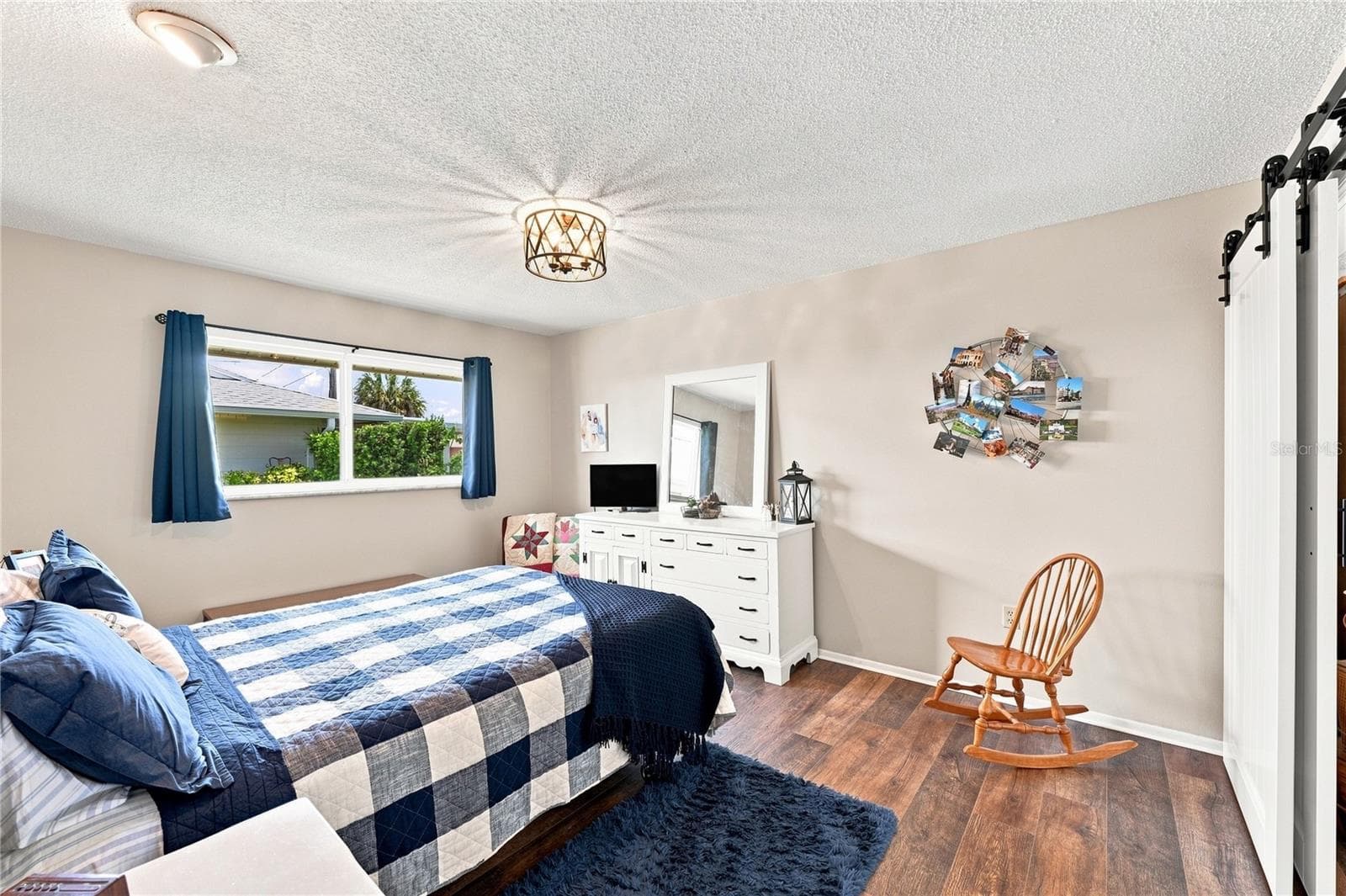 Inviting Primary Bedroom En Suite, Beautiful Laminate Oak Plank Flooring, New Modern Fixture, Sliding Barn Door to Bight Florida Room - 1405 HACIENDA DR, SUN CITY CENTER