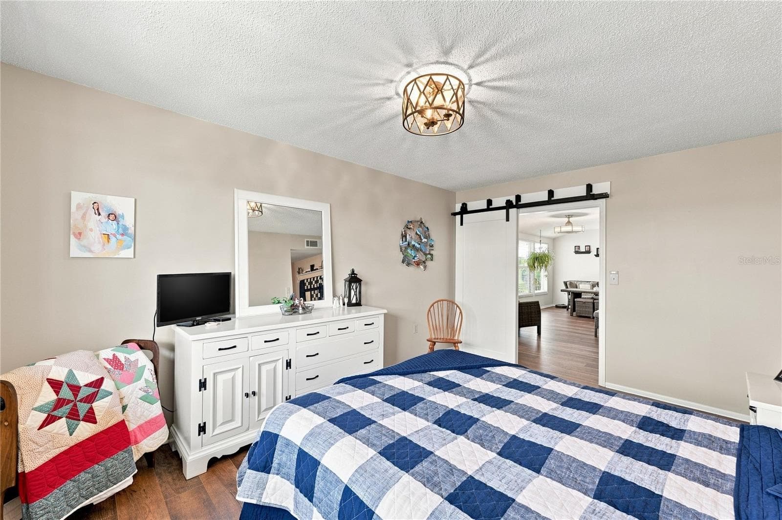 Inviting Primary Bedroom En-Suite, Beautiful Laminate Oak Plank Flooring, New Modern Fixture, Sliding Barn Door to Bight Florida Room - 1405 HACIENDA DR, SUN CITY CENTER