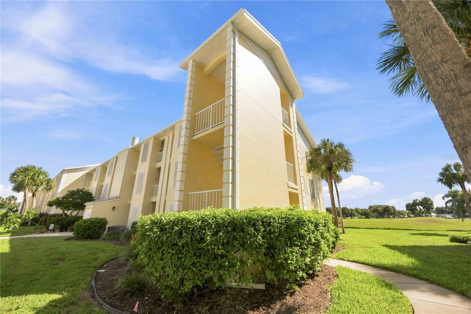 Tropical views greet you from the walkway, with palms and beautifully maintained green space beyond. - 406 CERROMAR CIR N #328, VENICE