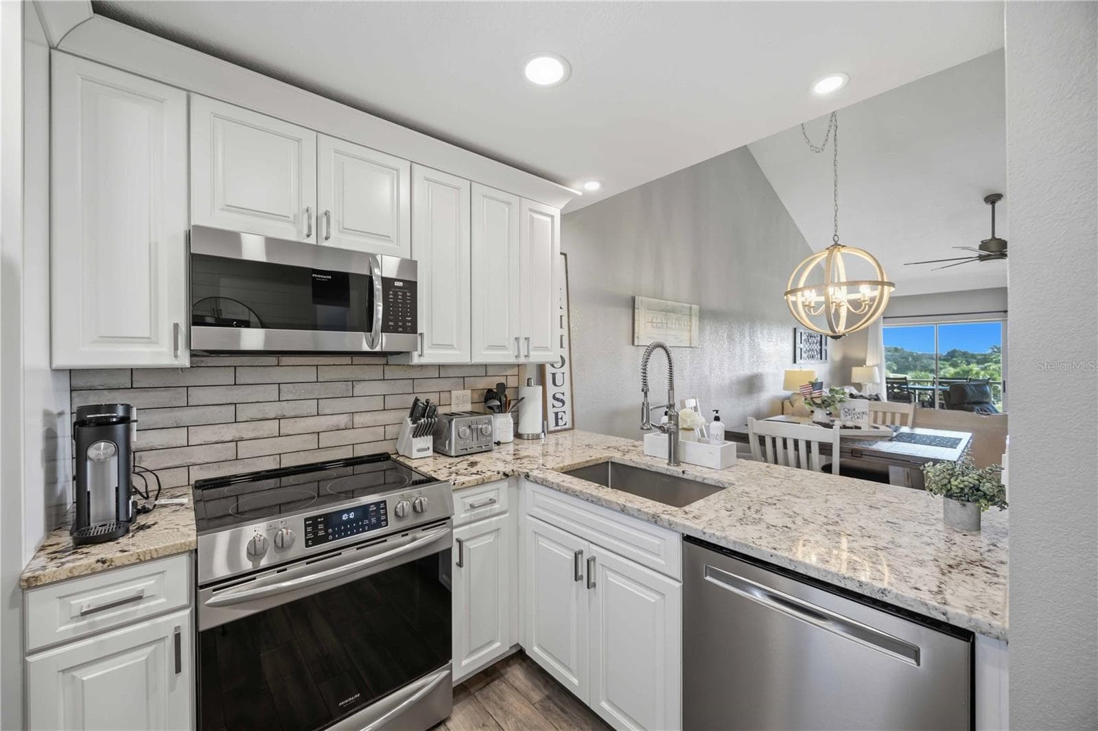Beautifully updated kitchen featuring crisp white cabinetry, stainless steel appliances, center island and wood-look flooring. - 406 CERROMAR CIR N #328, VENICE