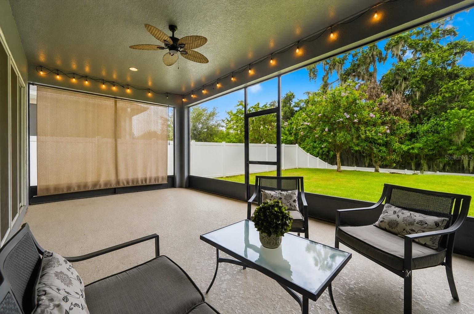 The expansive screened lanai with a retractable privacy shade invites effortless Florida living, from peaceful mornings overlooking the lush backyard to relaxed evenings entertaining under the glow of string lights. - 4791 RIVERWALK DR, ST CLOUD