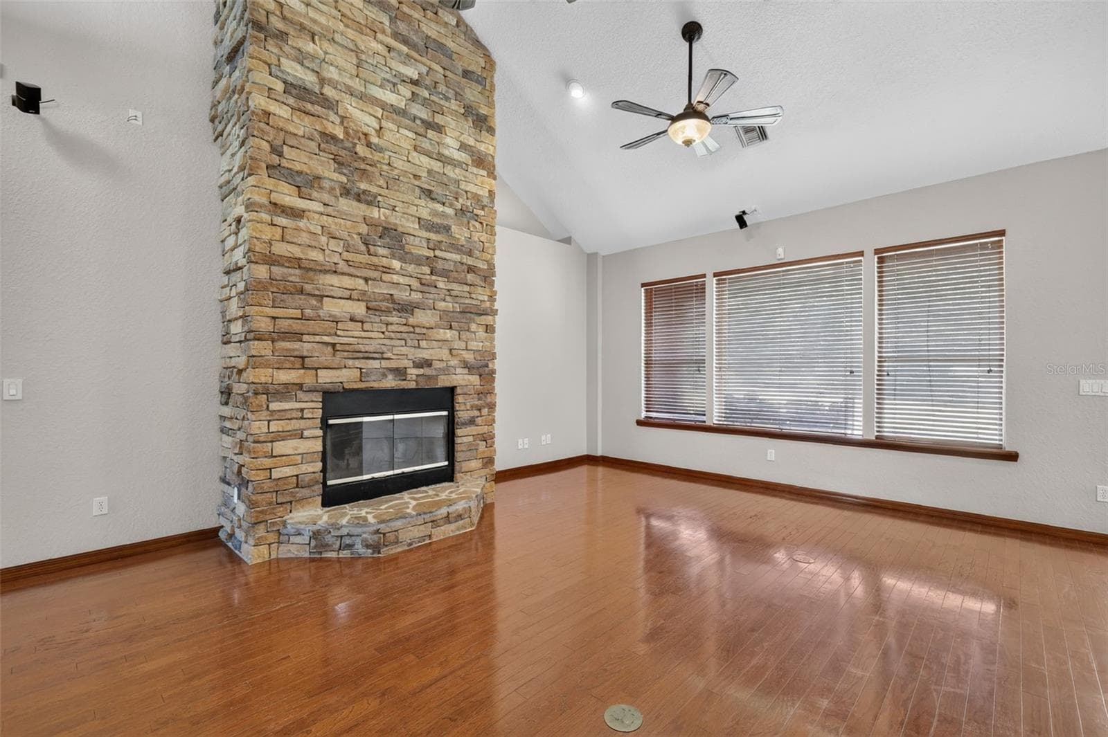 The stacked stone fireplace with glass doors creates a cozy gathering point, while oversized windows flood the room with natural light. - 4617 ROUND LAKE RD, APOPKA