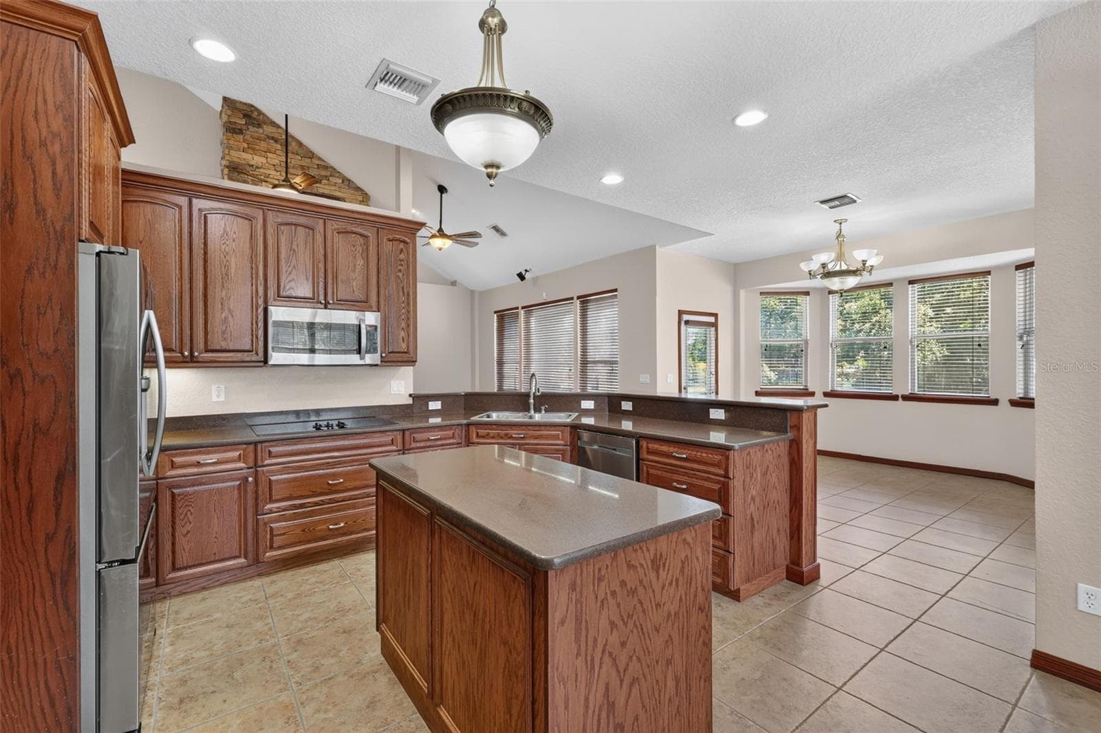 The chef's kitchen features a center island, abundant oak cabinetry, stainless steel appliances, and flows directly into a sunny breakfast nook. - 4617 ROUND LAKE RD, APOPKA