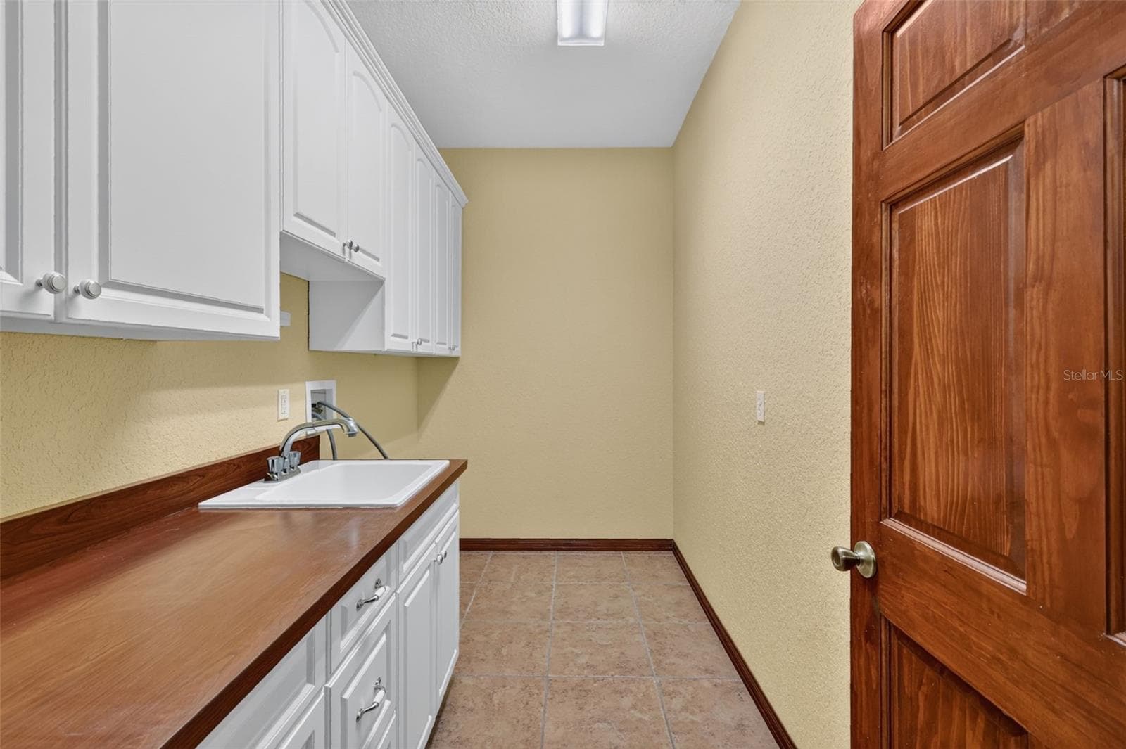 A dedicated laundry room with built-in cabinetry, a utility sink, and plenty of folding space keeps household chores effortless. - 4617 ROUND LAKE RD, APOPKA