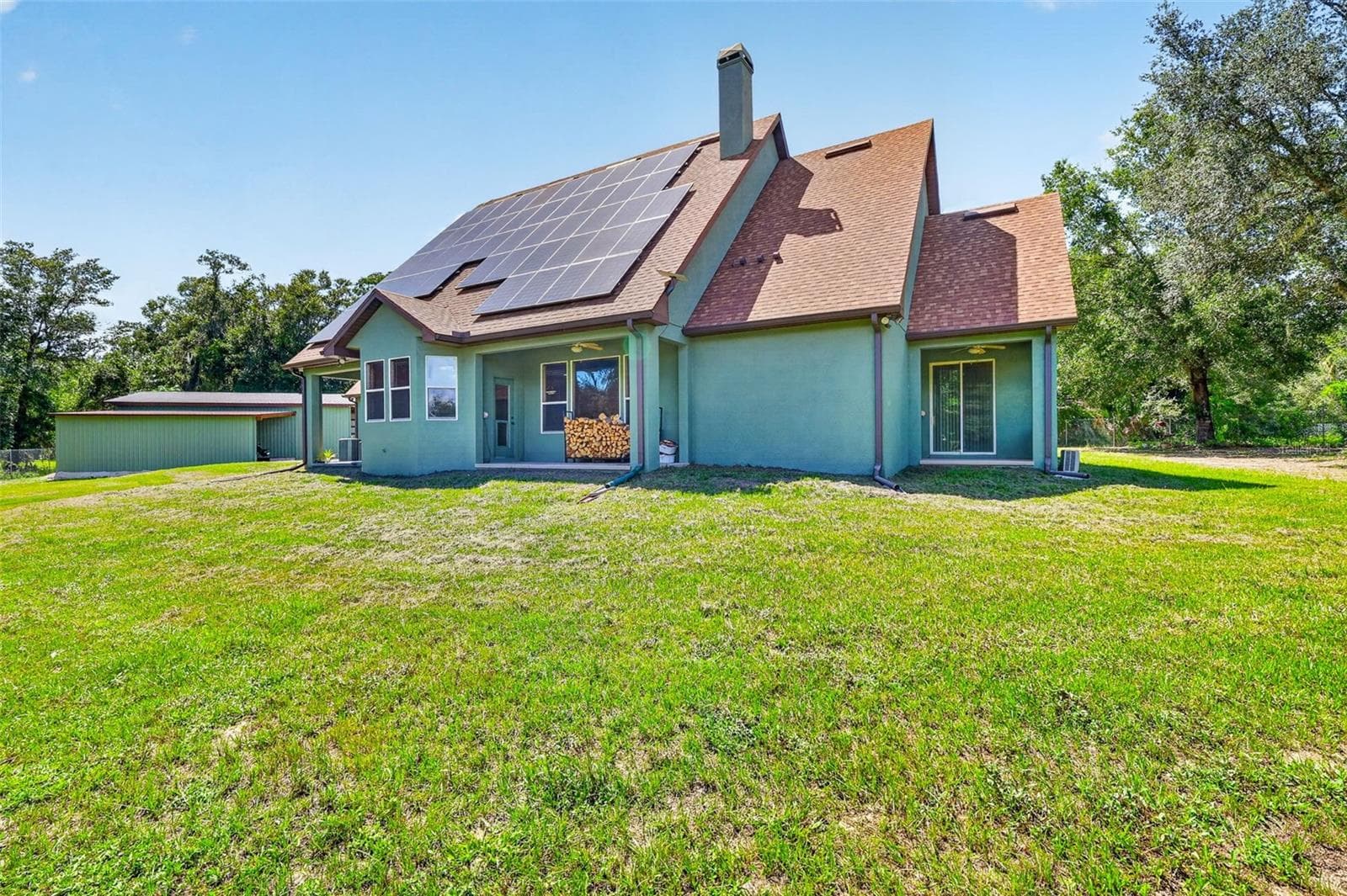 The rear of the home showcases the full scope of the owned solar array, multiple covered patios, and a massive backyard perfect for entertaining or future additions. - 4617 ROUND LAKE RD, APOPKA