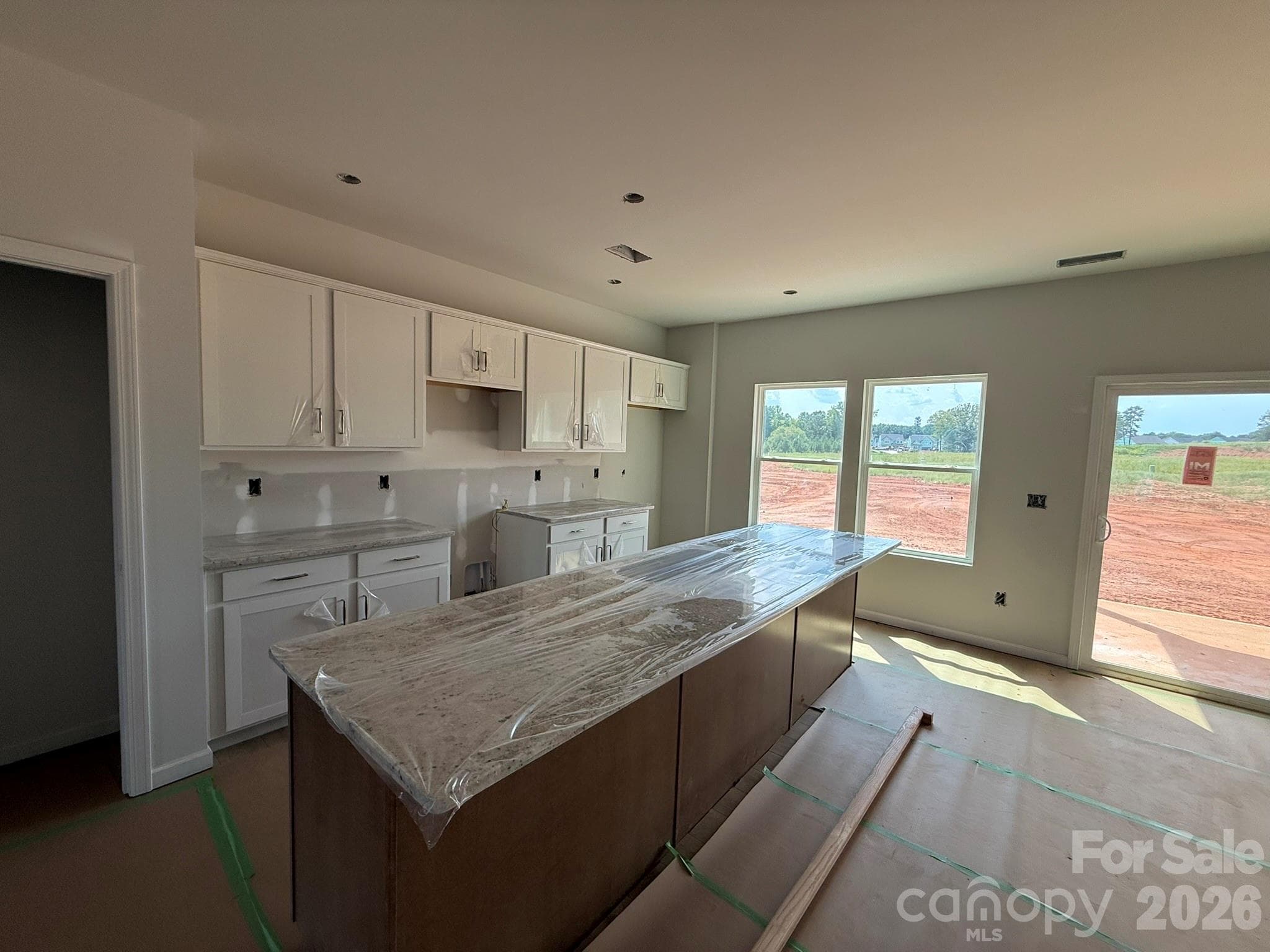 Kitchen features white surround cabinets and brown island with granite countertops - Charlotte