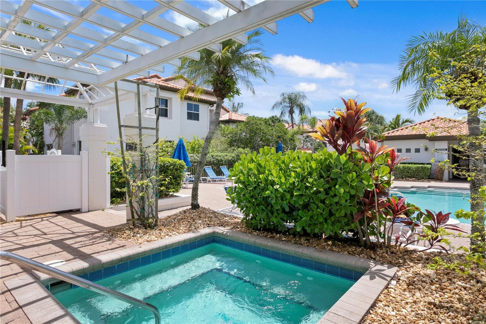 The hot tub is nestled under a charming pergola, surrounded by lush tropical landscaping. - 1116 SHIPWATCH CIR, TAMPA