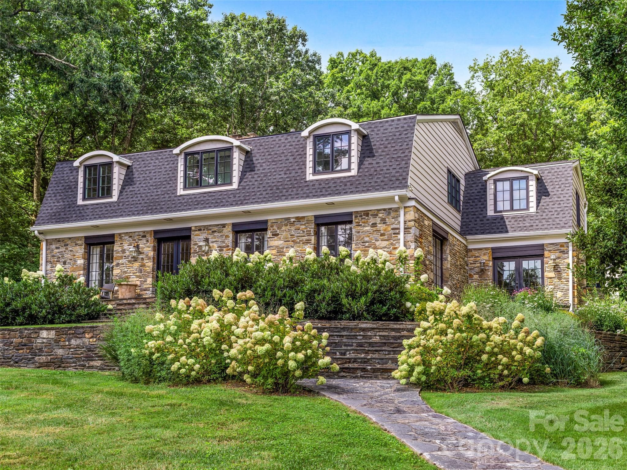 1912 stone exterior with stone paths and professionally designed gardens, surrounding the property. - Hendersonville