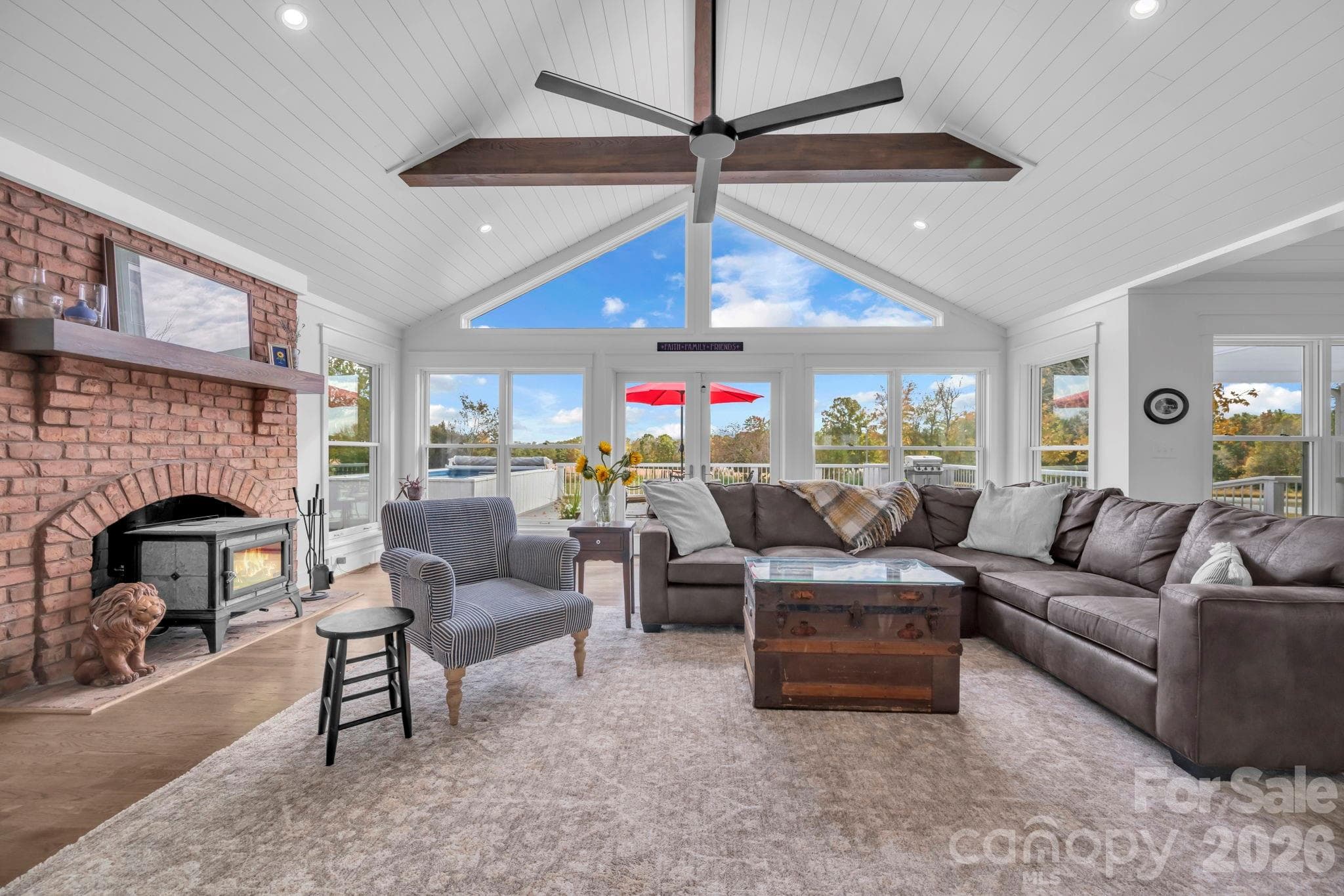 Great room w/ cathedral ceilings & exposed wooden beams, brick fireplace w/ Hearthstone wood burning cast iron stove, shiplap ceiling, and large gable window for natural light - 1260 Beaver Island Trail Road, Walnut Cove