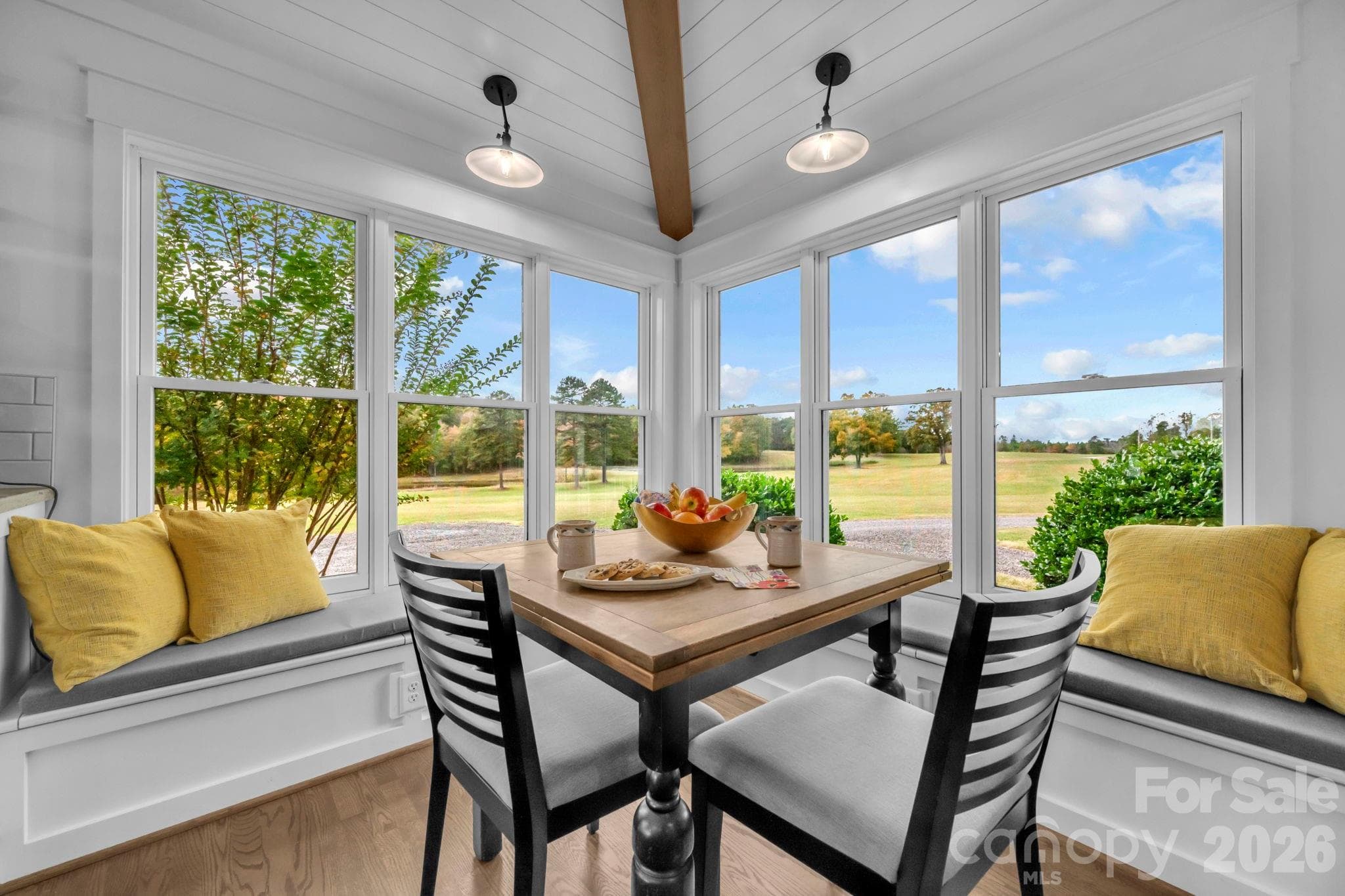 Breakfast nook w/ shiplap ceiling and exposed beam, built-in bench storage, and wall of windows for pasture views - 1260 Beaver Island Trail Road, Walnut Cove
