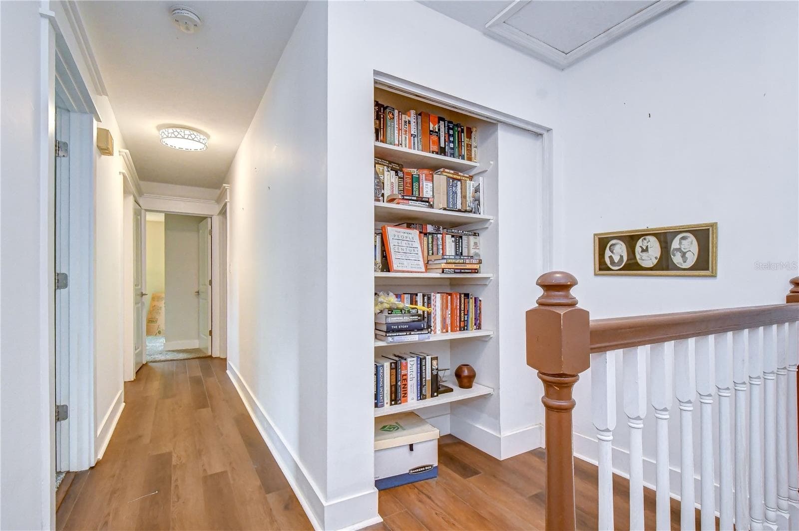 Upper hallway featuring custom built-in shelving and warm flooring. - 901 WOODVIEW DR, BRANDON