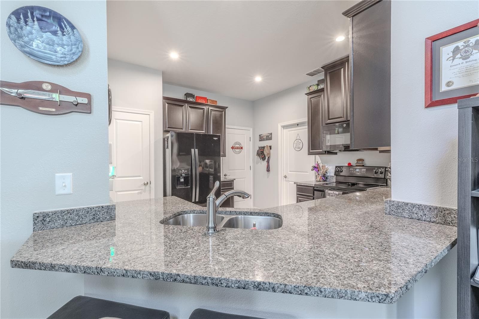 A granite-topped peninsula with a double-basin sink and breakfast-bar seating adds generous workspace while keeping the kitchen open to the adjoining living and dining area. - 3029 JACOB CROSSING LN, HOLIDAY