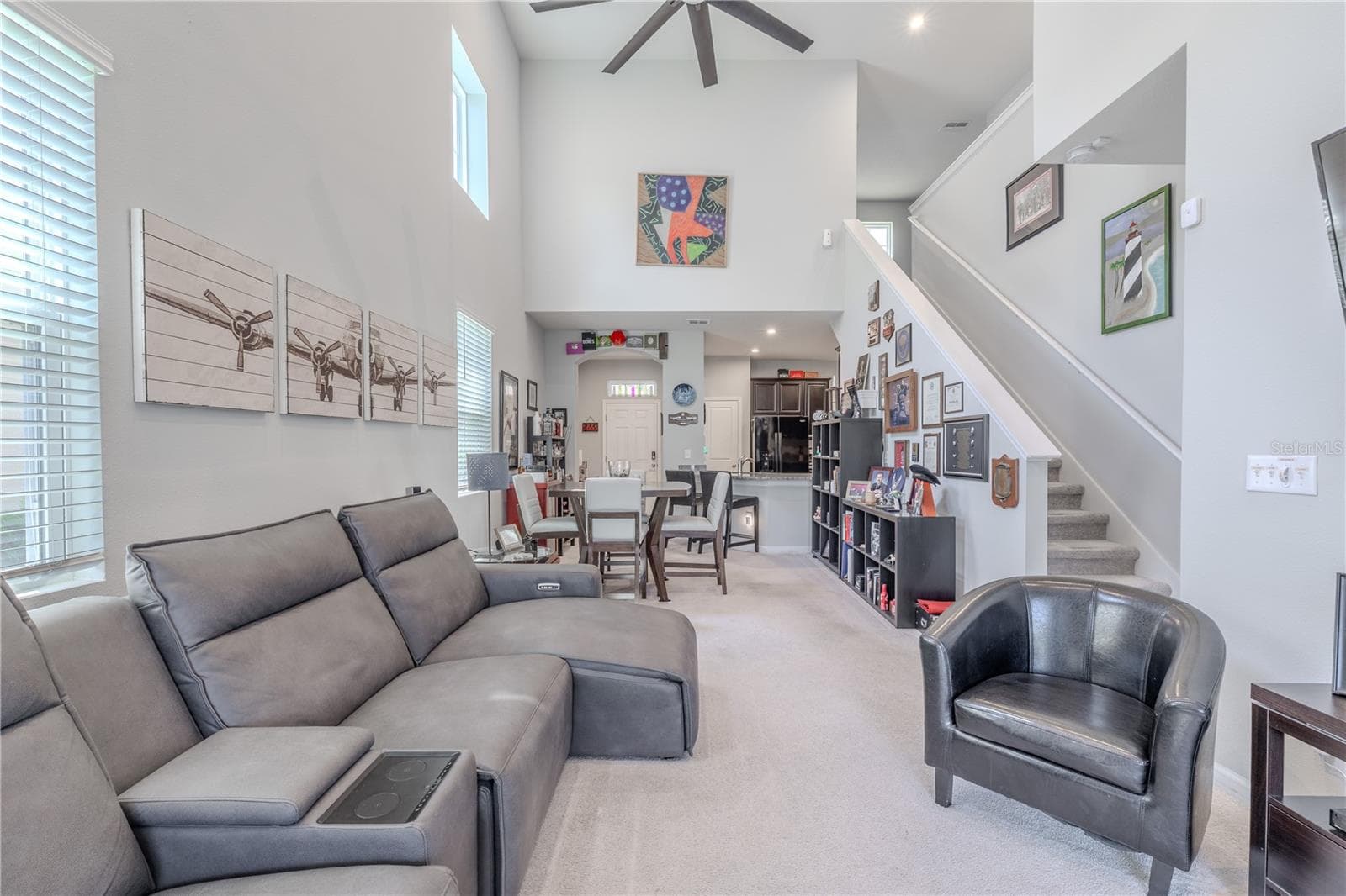 Dramatic ceiling height and clerestory windows give the main living area impressive volume, while the open layout connects the living room, dining space and kitchen with the staircase rising along one side. - 3029 JACOB CROSSING LN, HOLIDAY