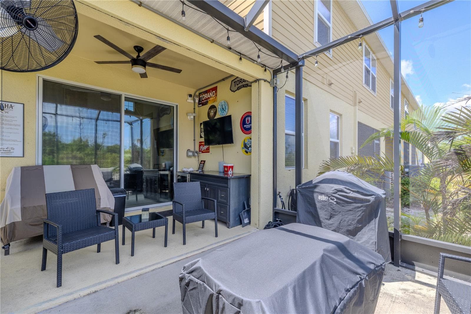 The covered lanai creates a shaded sitting area beneath a ceiling fan, while the screened extension adds generous space for grilling, entertaining and enjoying the tropical surroundings just outside the living-room sliders. - 3029 JACOB CROSSING LN, HOLIDAY