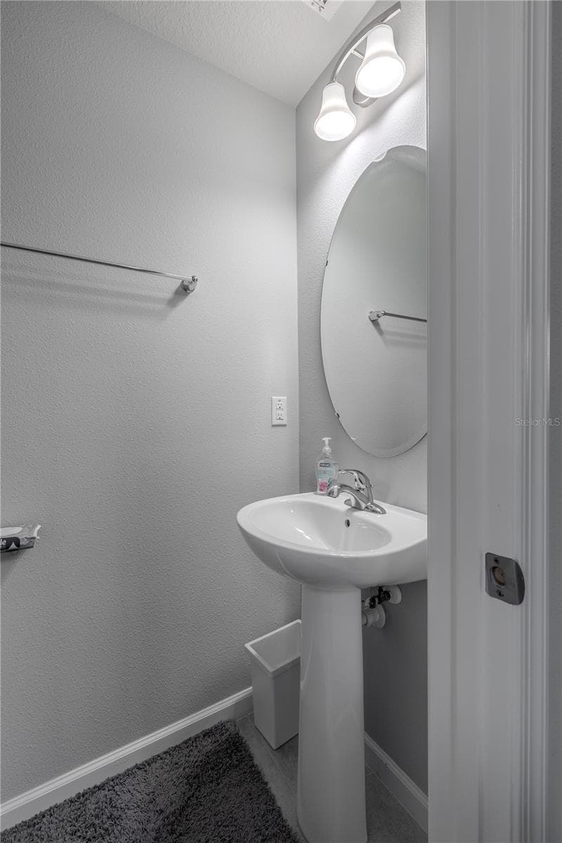 A convenient main-level powder room features a pedestal sink, oval mirror and neutral finishes. - 3029 JACOB CROSSING LN, HOLIDAY