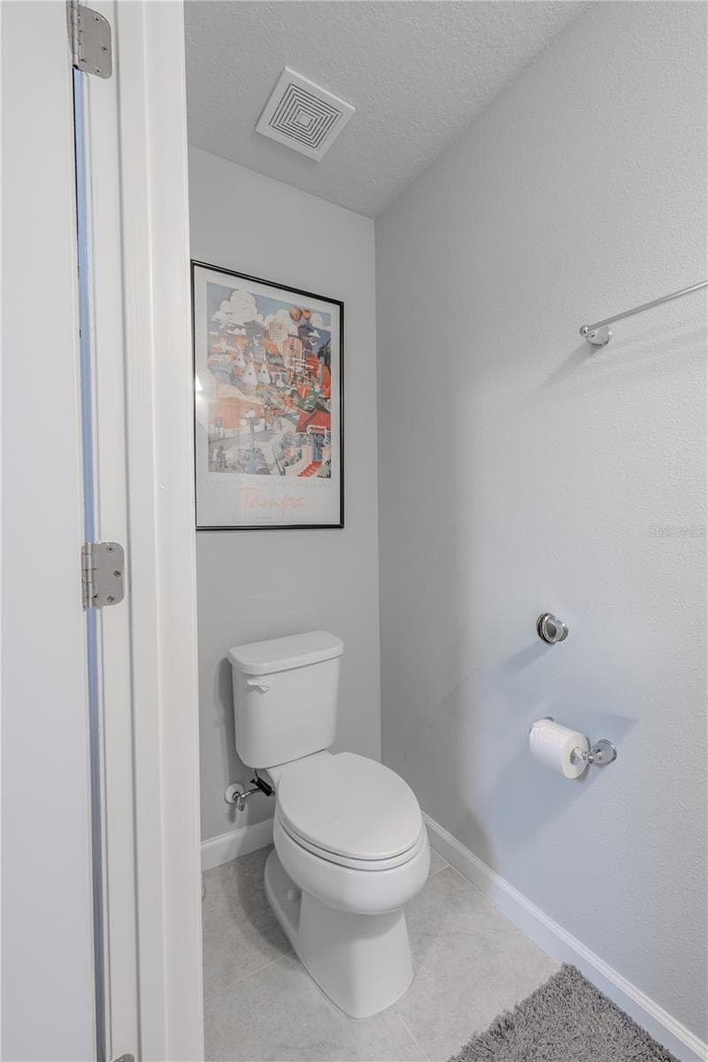 The main-level powder room continues the home’s neutral palette with tile flooring and a simple, clean layout for guests. - 3029 JACOB CROSSING LN, HOLIDAY