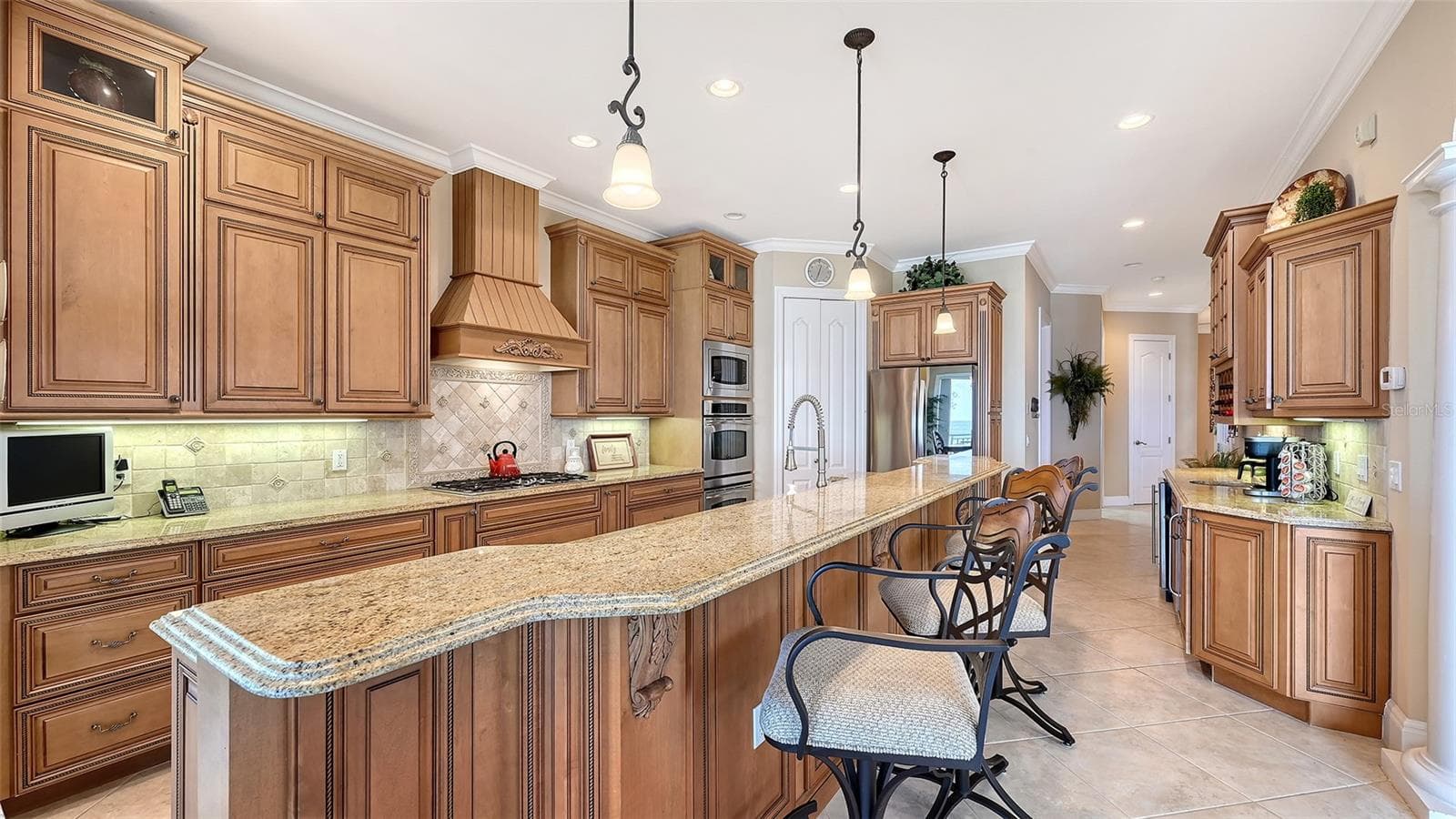 Gorgeous kitchen with wood cabinetry, granite counter tops, GE Profile and LG appliances. Gas stove, double oven, walk-in pantry is behind the white doors Coffee bar area with wet sink and two wine/beverage refrigerators on right. - 106 74TH ST #100, HOLMES BEACH