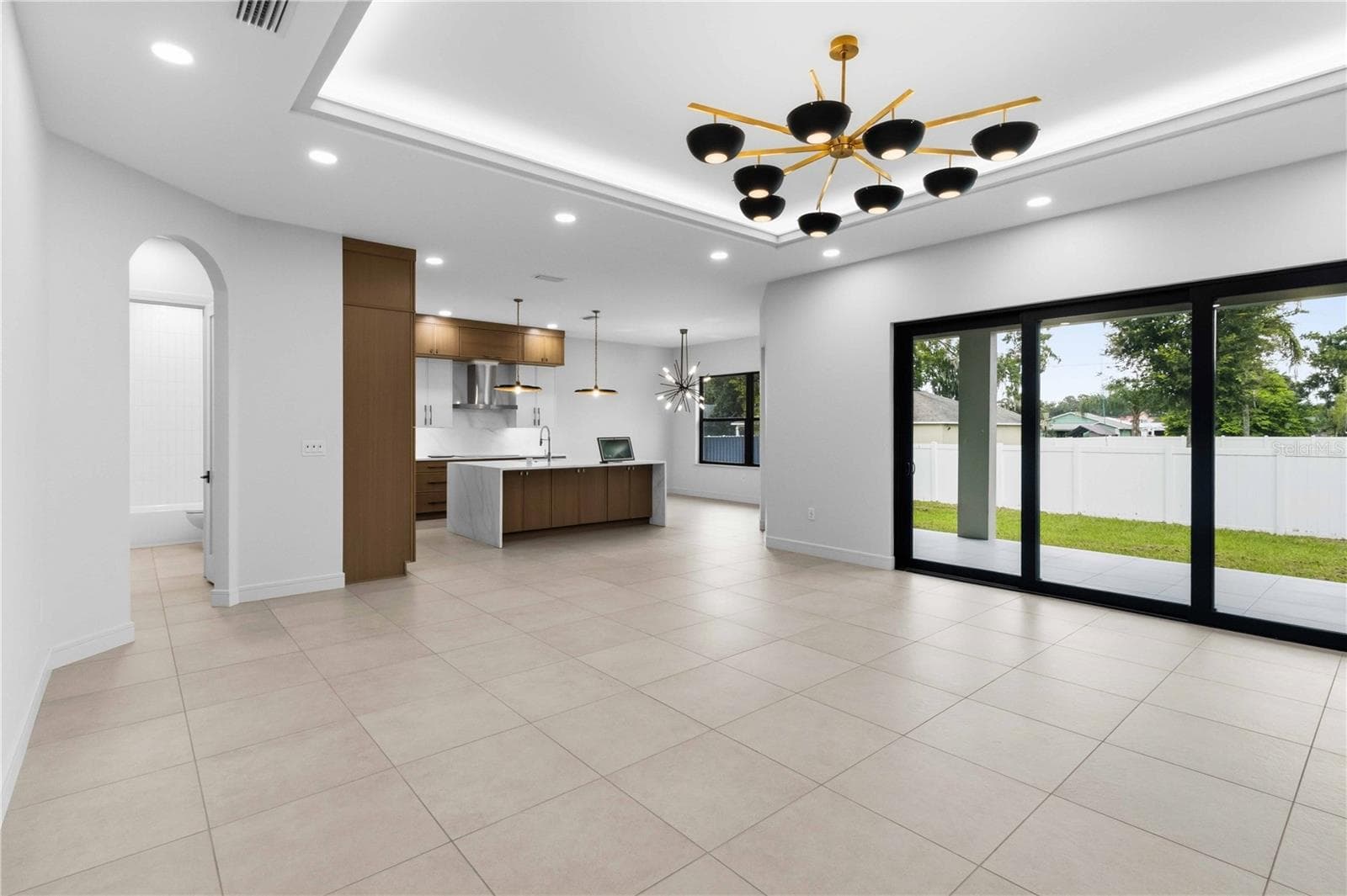living room with an illuminated tray ceiling and statement chandelier elevate the space - 104 S MAKI RD, PLANT CITY