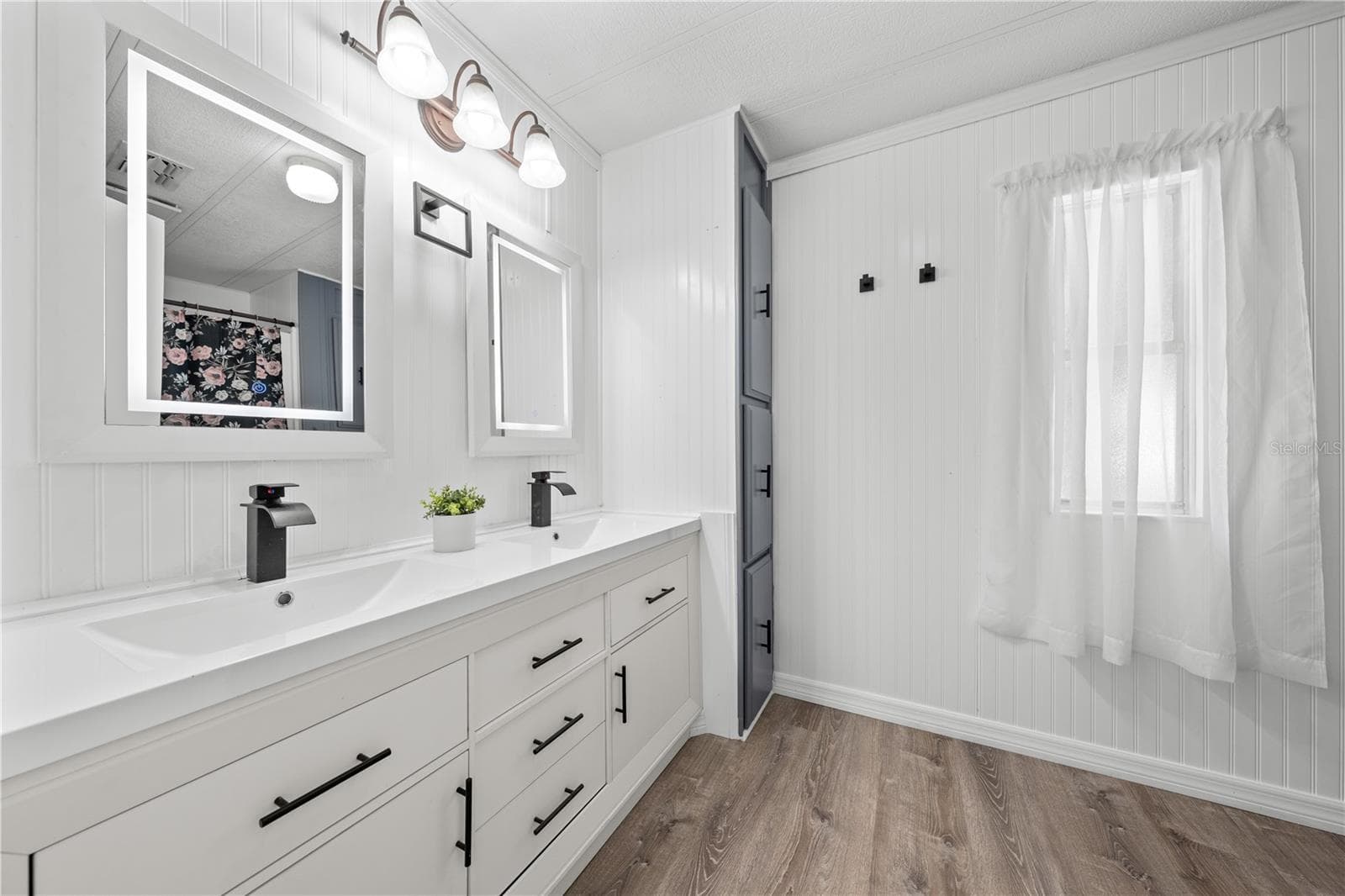 Primary's bathroom with new, double vanity, LED mirrors, waterfall faucets and floor to ceiling storage. - 5601 LAKE LIZZIE DR, ST CLOUD