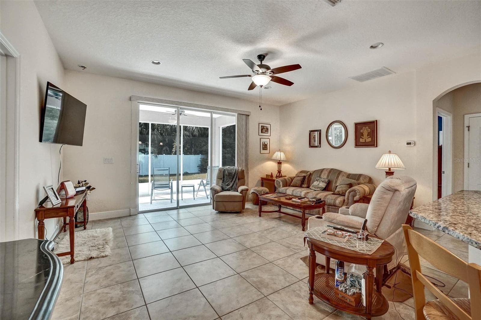 Bright living room overlooking the covered patio through sliding glass doors. - 1720 LADY FERN TRL, DELAND