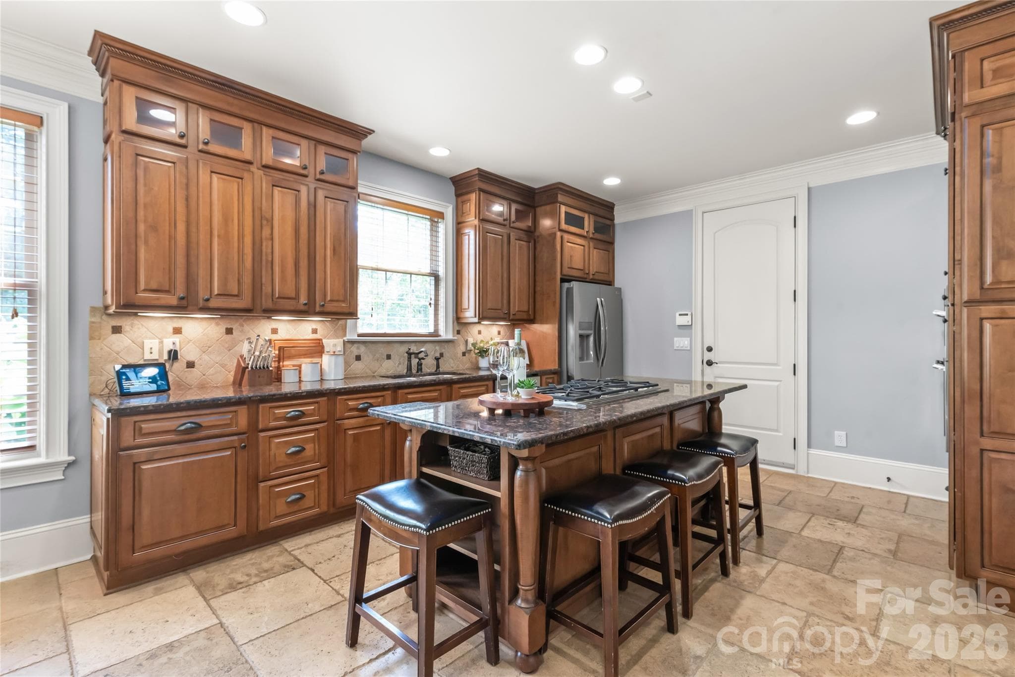 The gourmet kitchen features cabinetry extending to the ceiling with glass-front uppers, premium finishes, and seamless flow into the living space. - 7320 Summerlin Place, Charlotte