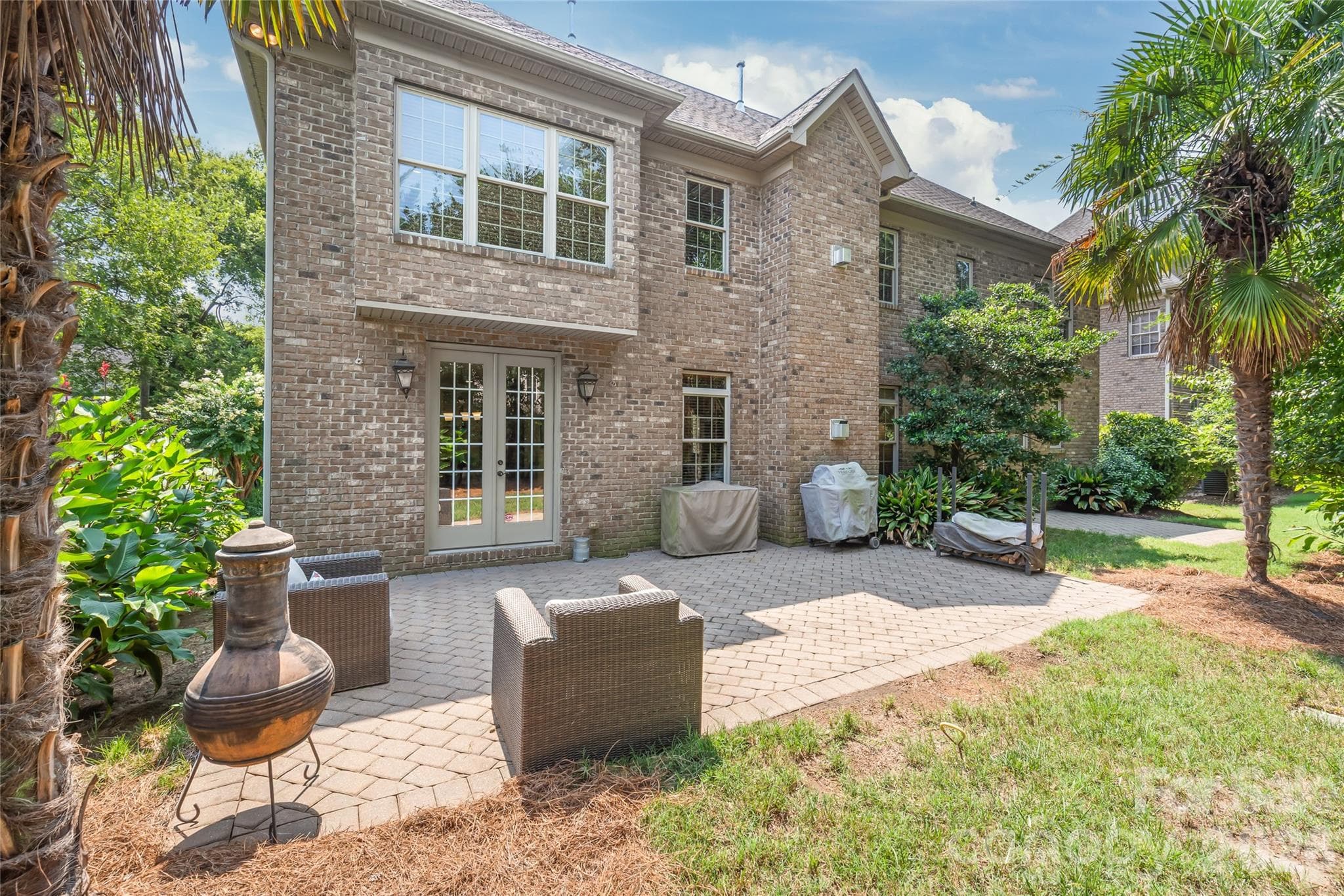 A private backyard retreat featuring two stone patios, perfect for outdoor dining and entertaining under the open sky. - 7320 Summerlin Place, Charlotte